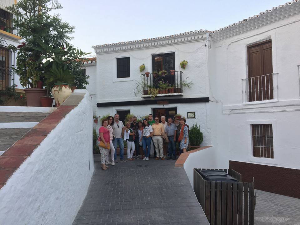 Personas posando en frente de una casa blanca